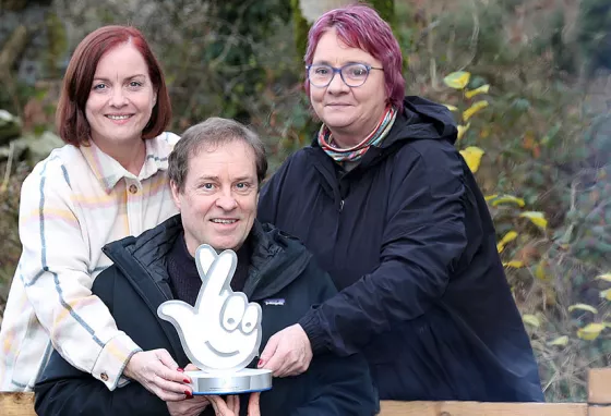 Three people hold an award