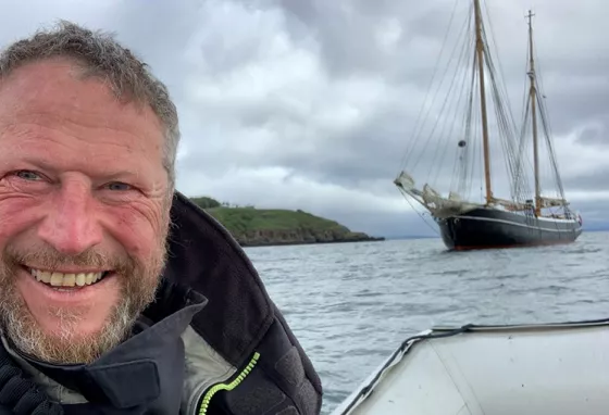 Person smiling at camera with boat in the background