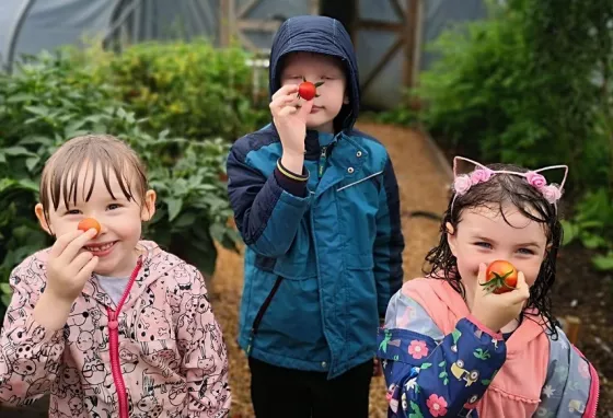 The Green Valley Conservation and Heritage project Three children hold tomatoes to their noses
