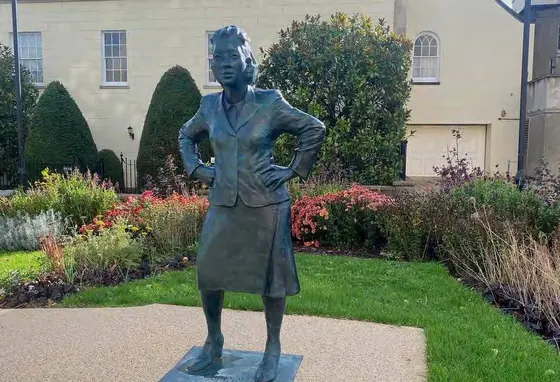 Life-sized statue of a woman in a small, landscaped garden