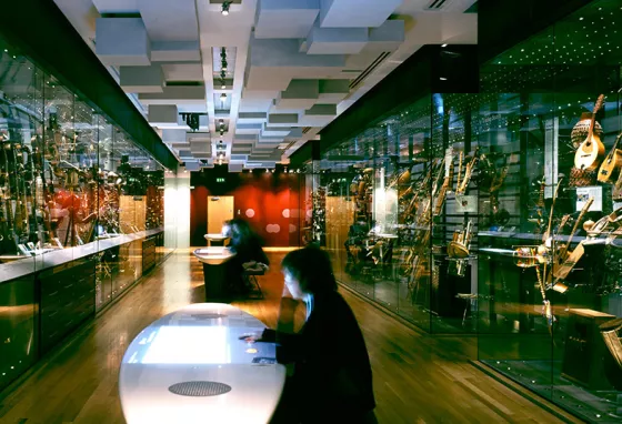 People sitting at tables with modern displays of musical instruments