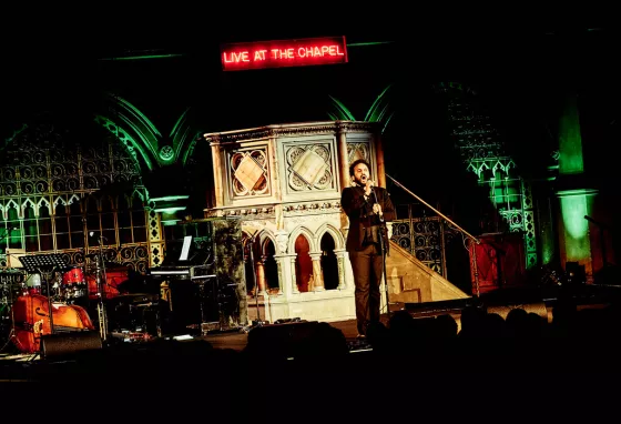 Nish Kumar performing at Union Chapel in front of pulpit and Live at the chapel LED sign Nish Kumar performing at Union Chapel in front of pulpit and Live at the chapel LED sign