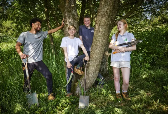 Young people standing in nature with gardening tools