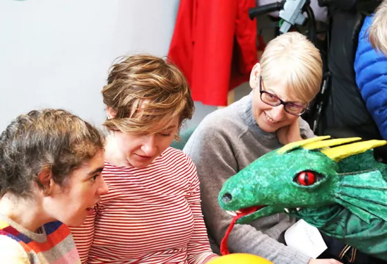 Learning Together: making collections accessible through multi-sensory stories Young girl interacting with a dragon puppet during a PAMIS story telling session