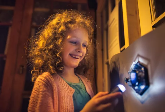 A child interacting with one of the Reimagining Reality exhibits and shining a light onto a shape on the wall.