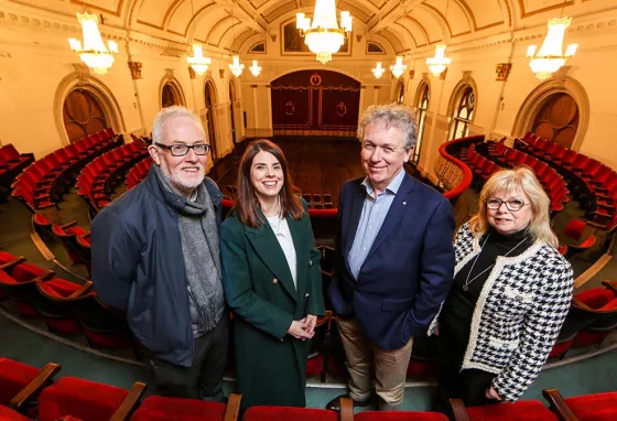 Four people stand in a grand hall