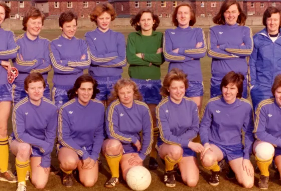 Women's football team face the camera in two rows - one standing behind, one kneeling in front.