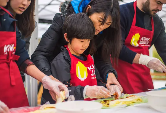 A child being shown how to make kimchi