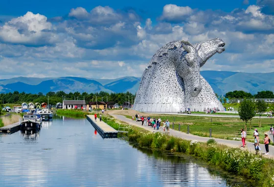 The Falkirk Kelpie sculptures, with boats on the canal and people walking along the paths