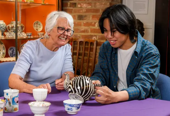 An older woman and a young adult man looking at ceramics