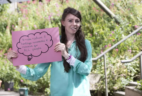 How do we involve young people in nature? Young woman holding sign