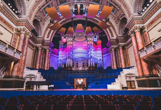 The interior of Leeds Town Hall with someone playing the organ on stage.
