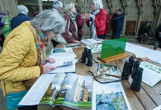 An older woman looks at magazines and leaflets on a table in a busy church