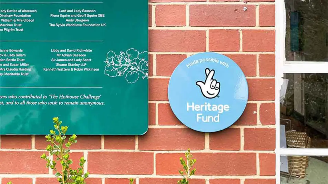 The stamp is mounted on a brick wall next to signage