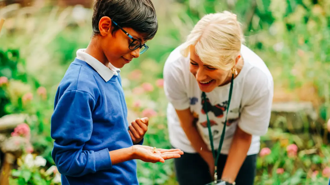 A boy holds a moth with a woman smiling at him