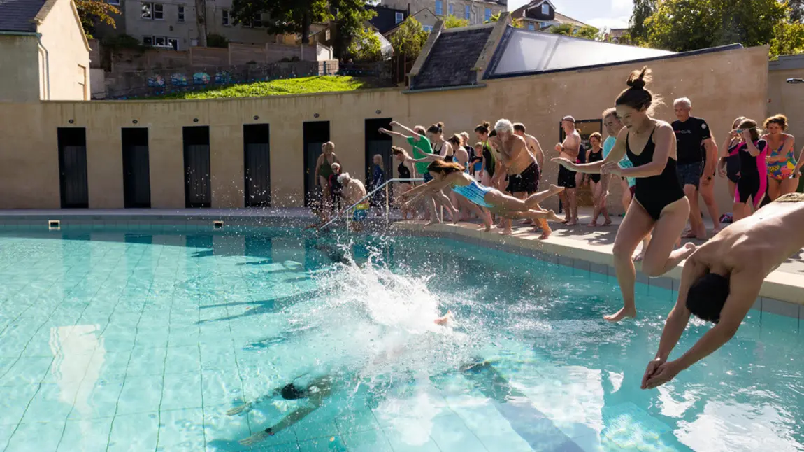 A group of people jump into the newly opened pools on a sunny day