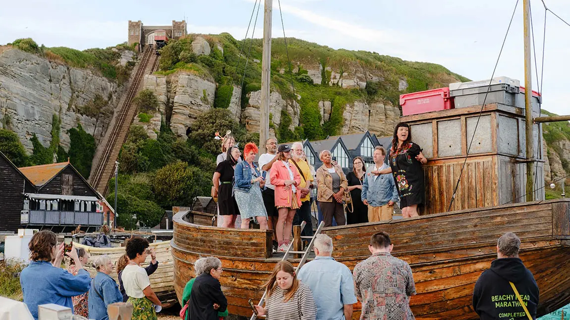 A group of people standing on the deck of a small wooden boat