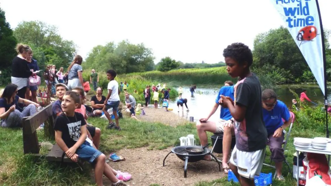A group of children and adults doing outdoor activities by a river