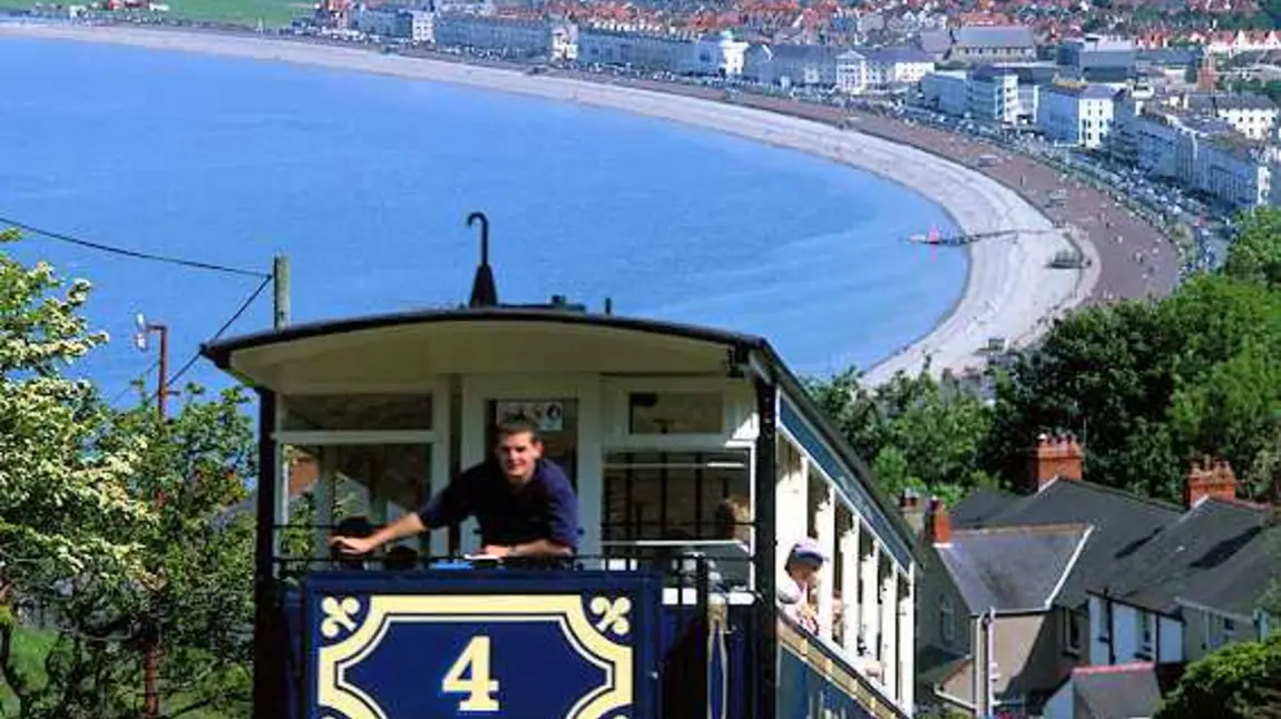 The tram on its way to the summit with a view of a beach below