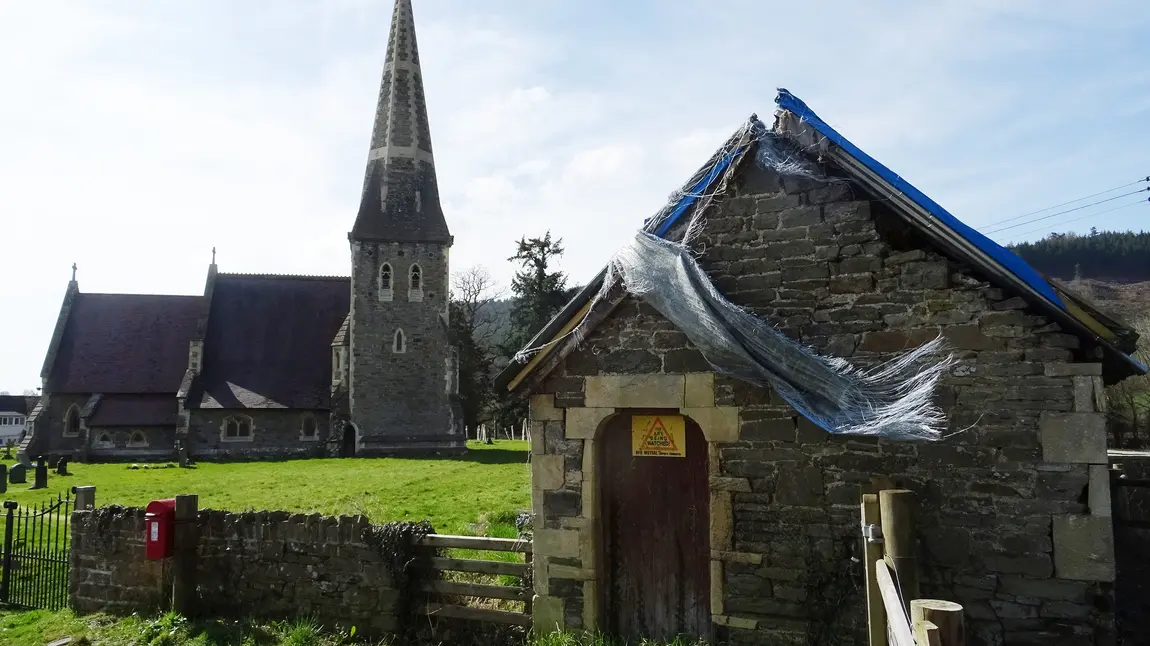 Tŷ’r Meirw Bochrwyd gydag Eglwys Sant Cynog yn y cefndir 