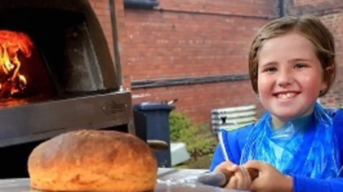 Young child making traditional bread in historic oven Young child making traditional bread in historic oven
