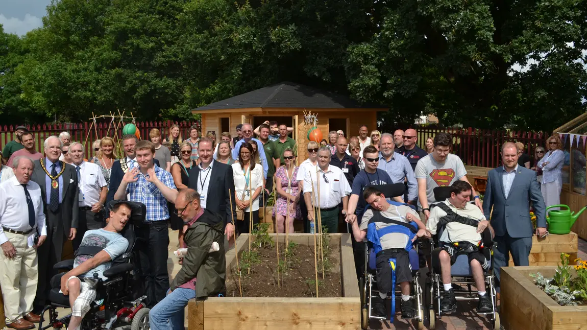 People gather around the raised beds in the community garden