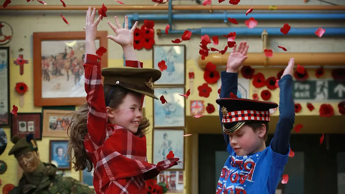 Children jumping and throwing poppies