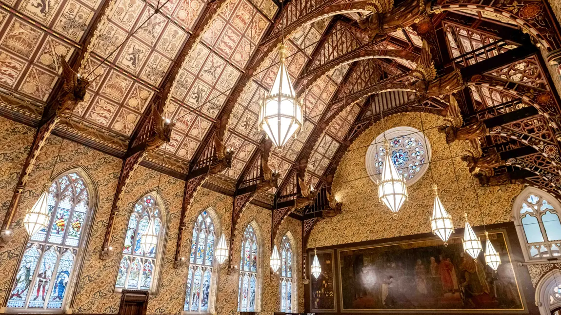 The interior of the Great Hall at Rochdale Town Hall, with decorative ceiling panels and gold angel statues held by wooden beams.