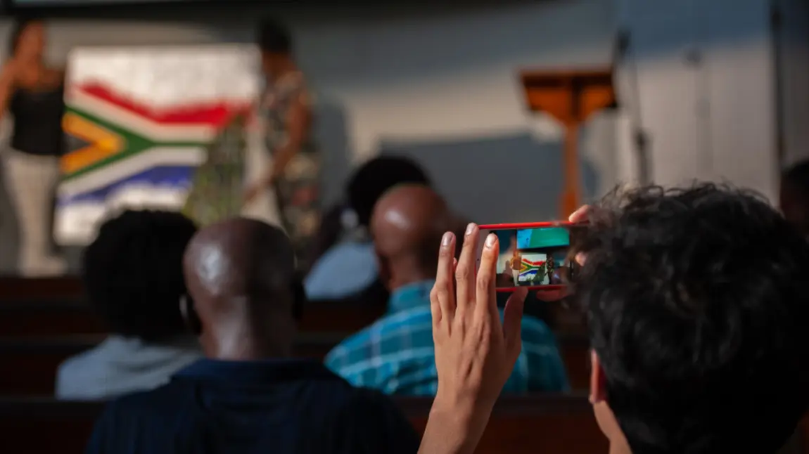 Person taking a picture of the South African flag on a phone camera at The Anti-Apartheid Legacy: Centre of Memory and Learning event