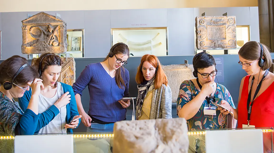 Six people using devices at a museum exhibition 