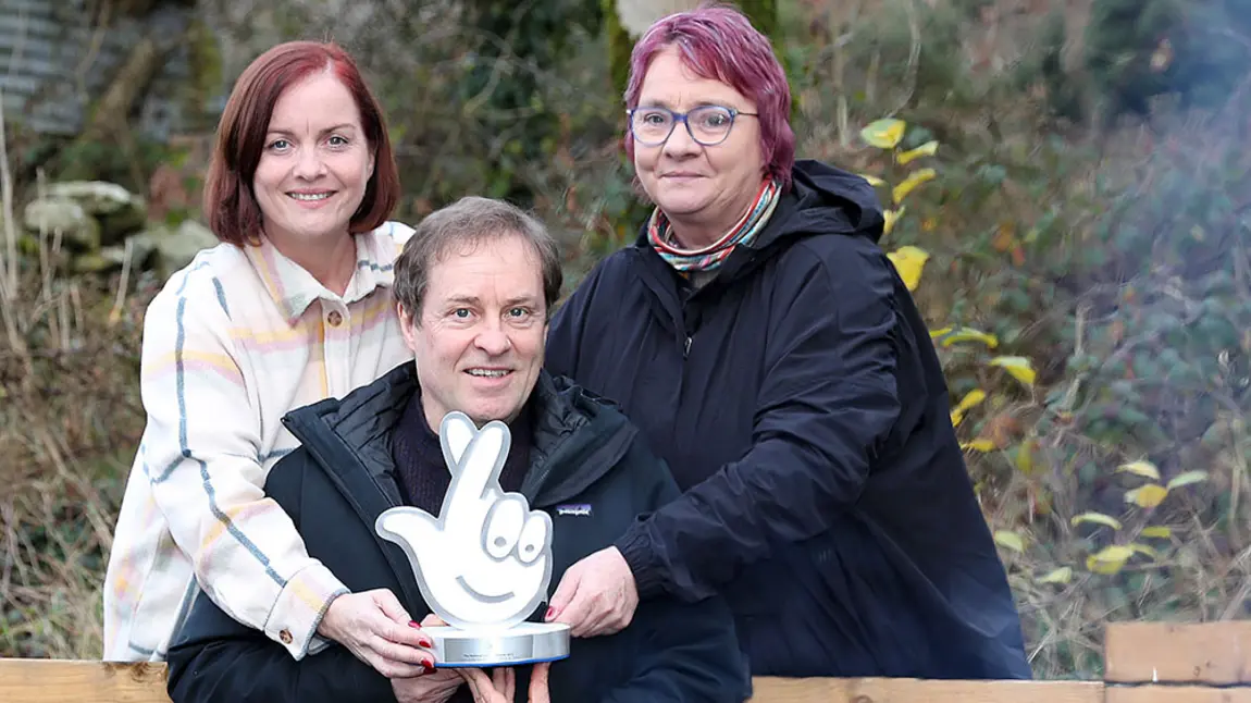 Three people hold an award