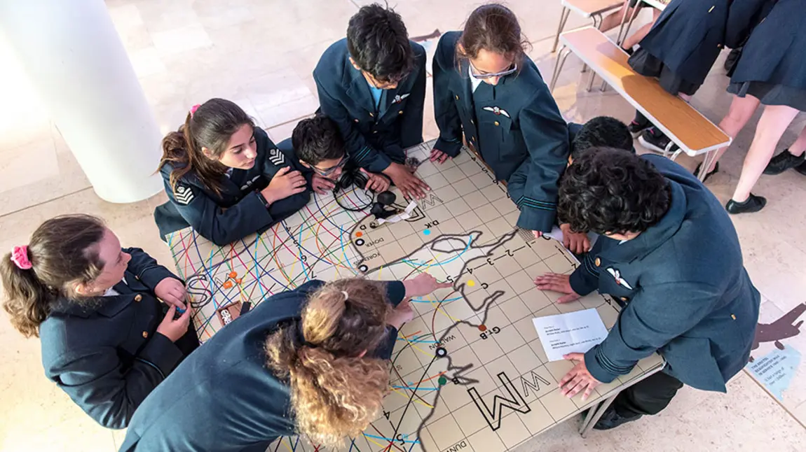 children gather round map of England