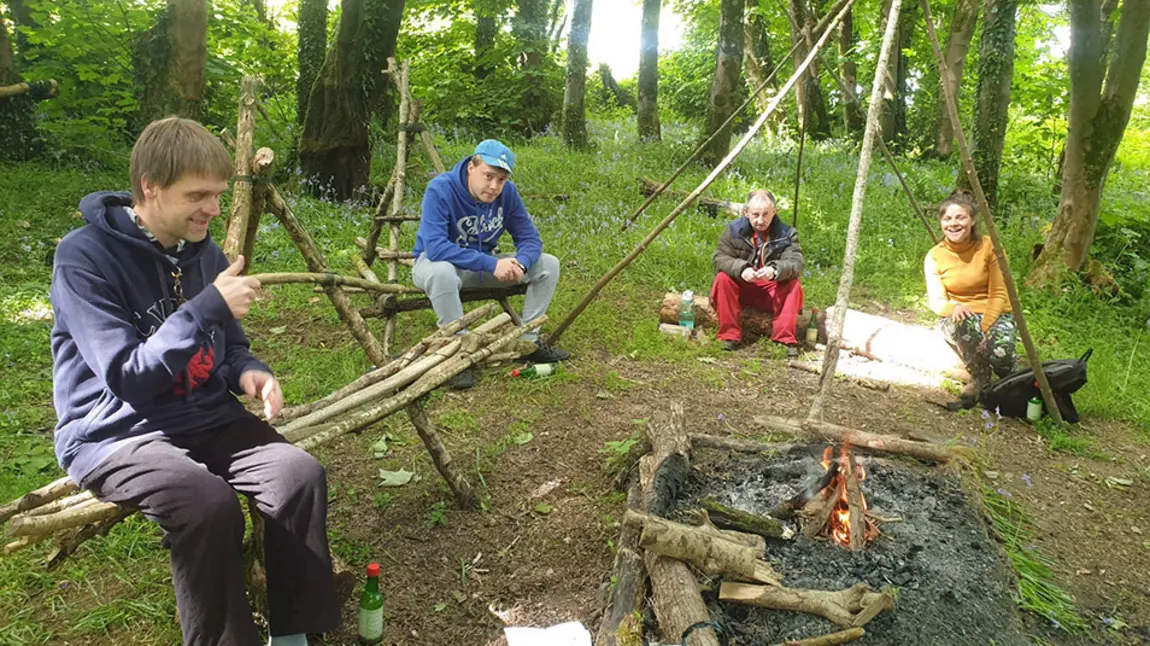 People chat round a campfire in woodland