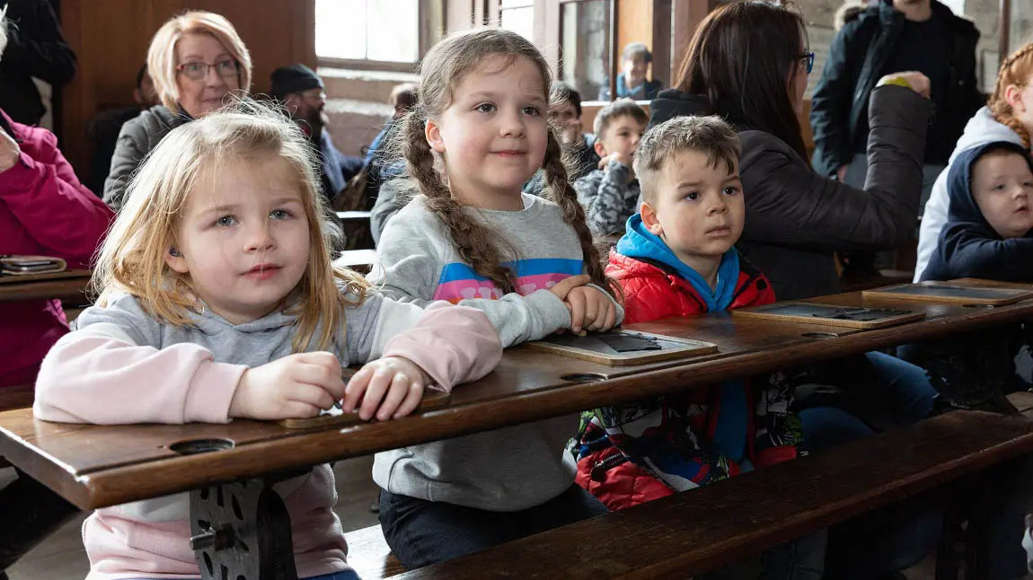 A row of children on a bench in an old school setting