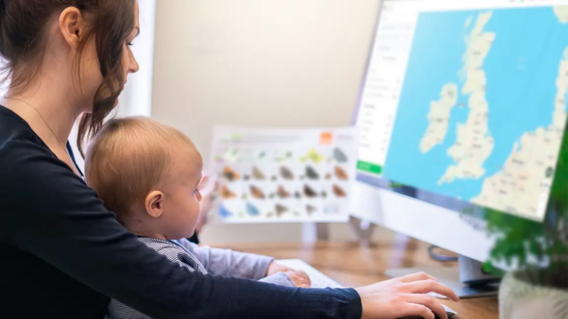 Adult and baby in front of computer showing map of UK