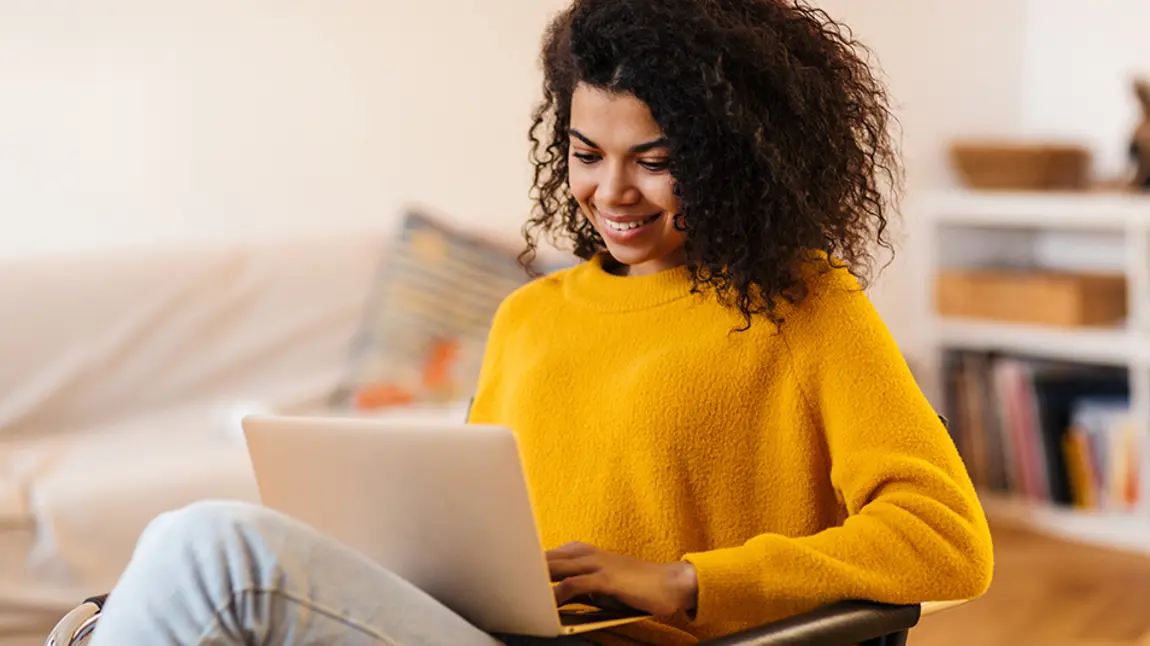 Young woman smiling as she looks at a laptop screen