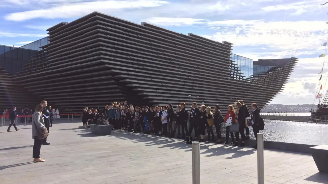 A group of people standing outside the V&A Dundee building