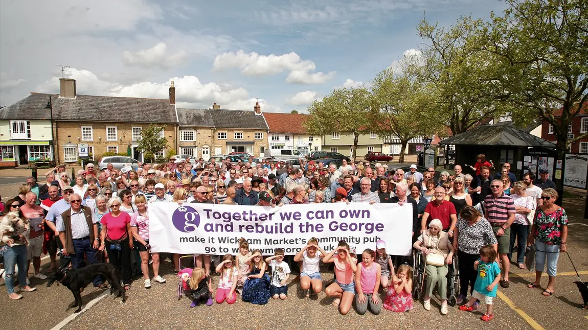 Wickham Market community holding up a banner to save The George pub.