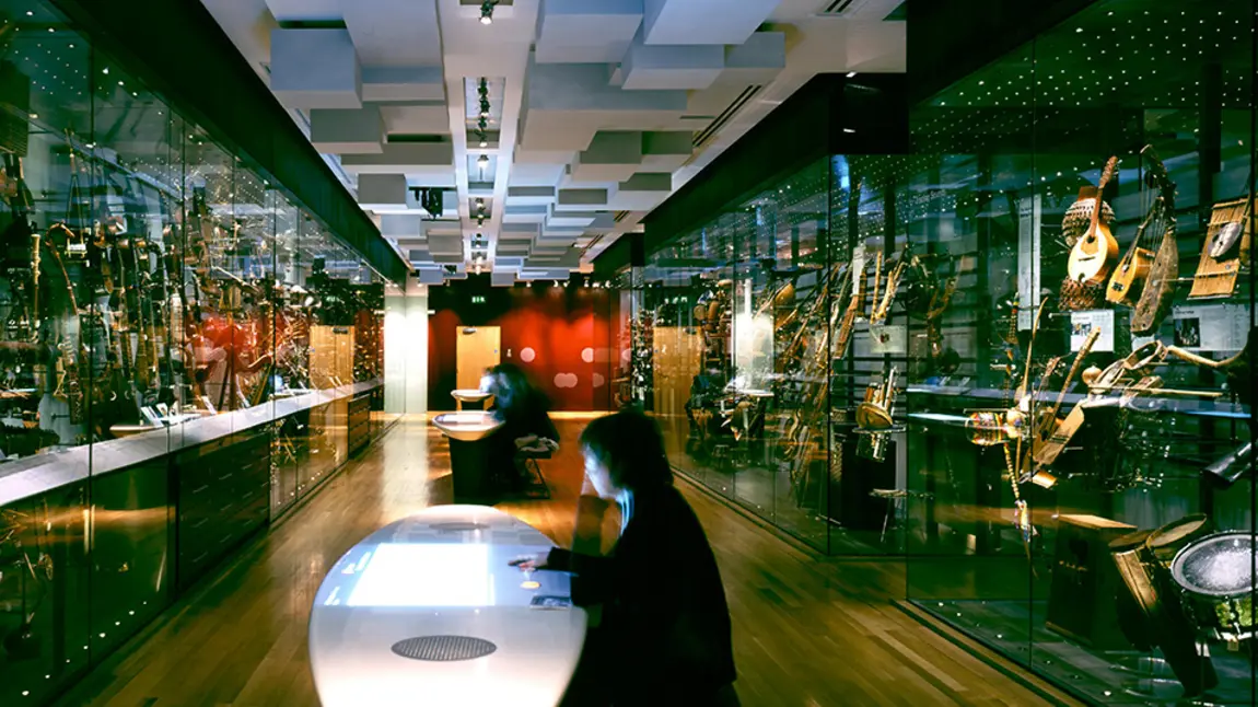 People sitting at tables with modern displays of musical instruments