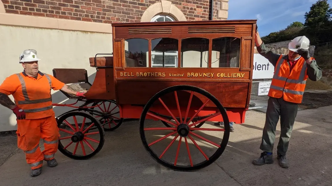 Two workmen standing either side of the horse-drawn ambulance