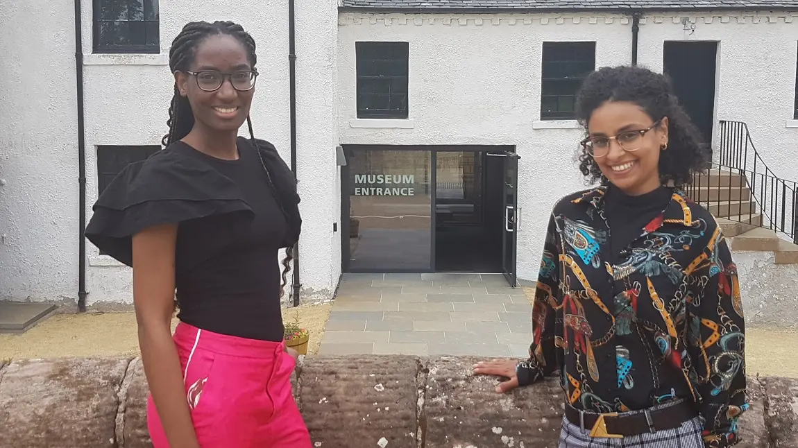 Two people smiling and standing in front of a museum entrance