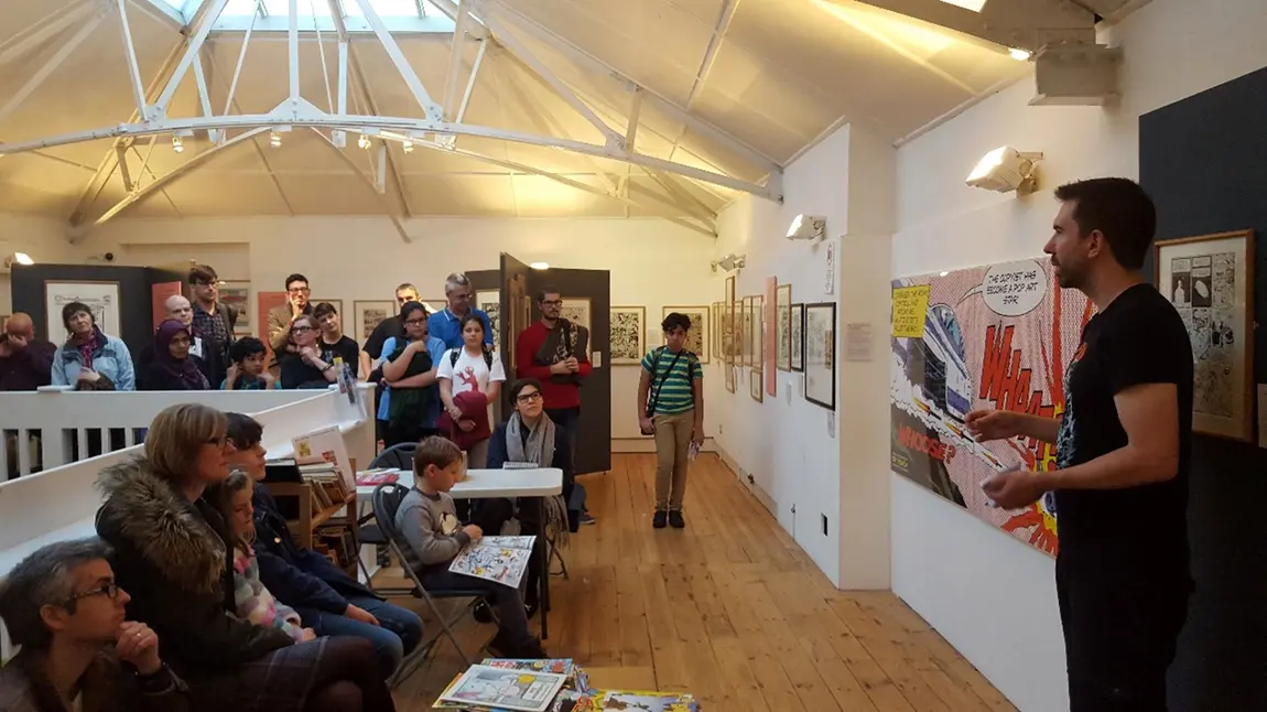 A comic Creator giving a talk in front of a crowd at The Cartoon Museum