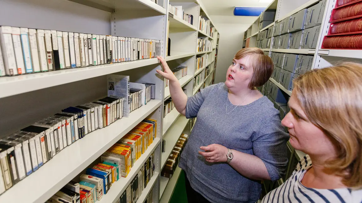 Two people looking at tapes on shelves