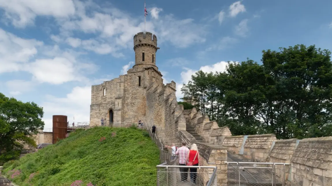 People walking up steps to a castle with turret