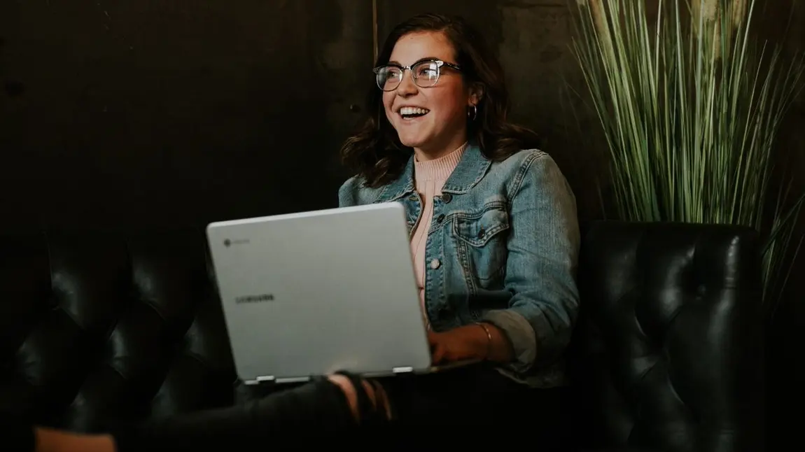Person using laptop whilst smiling