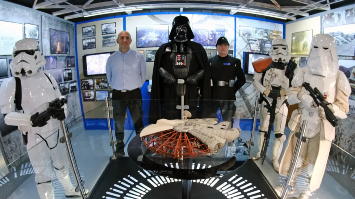 Storm Troopers and Darth Vader standing around a model of the Millennium Falcon