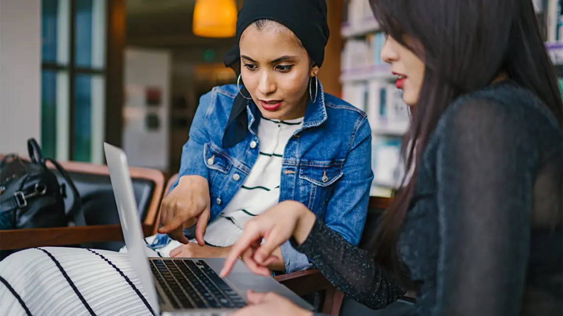 Two people look at laptop