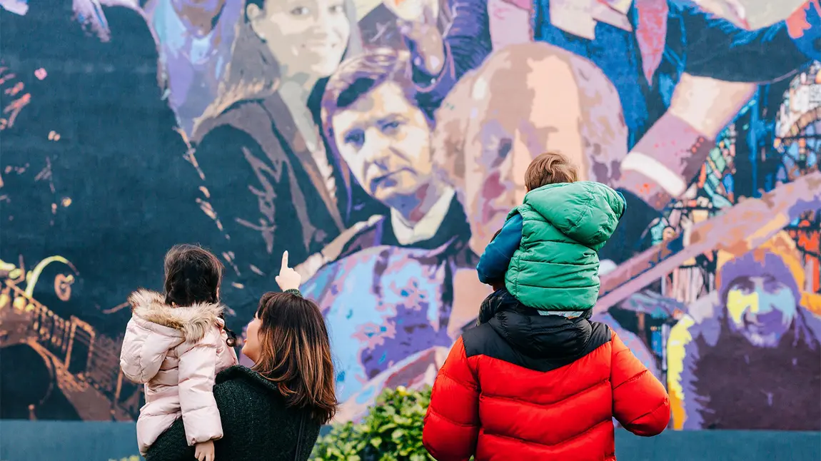 Two adults and two children looking at a wall mural