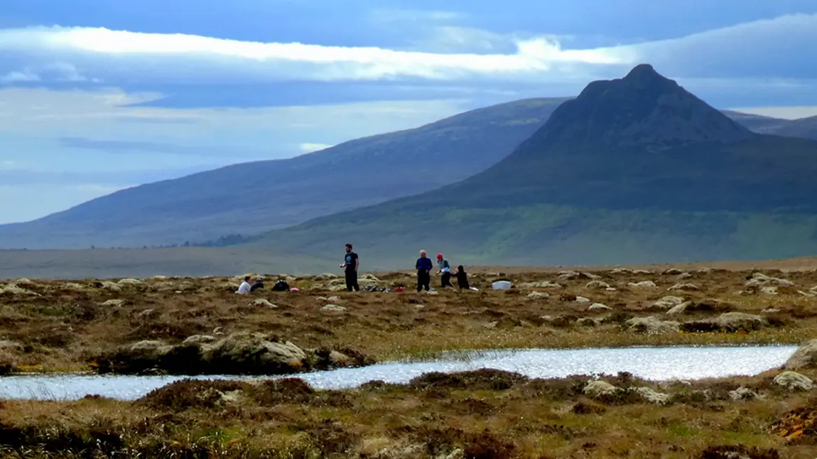 People in natural landscape with mountain in distance