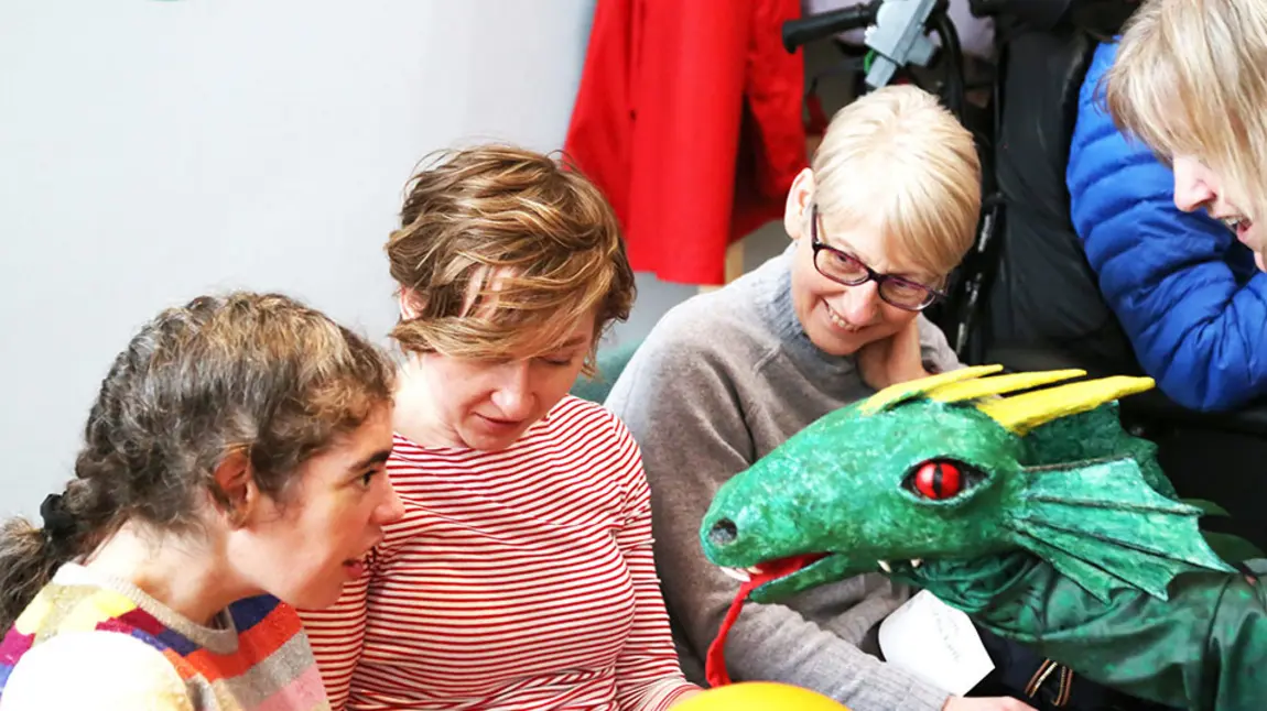Young girl interacting with a dragon puppet during a PAMIS story telling session